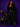 Lady Q’s Corner black longline wool-blend coat worn by a smiling woman with black leather trousers and a chain bag.