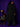 Lady Q’s Corner black longline wool-blend coat with back button-tab detail worn by a woman against a purple wall
