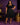 Lady Q’s Corner black pleated midi skirt worn by a smiling woman with a matching black top and heels in a purple room.