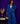 Lady Q’s Corner denim blazer and wide-leg trouser set in classic blue with gold buttons worn by a smiling woman.
