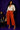 Lady Q’s Corner rust-orange high-waisted wide-leg trousers with button detail, worn with a cream shirt and heels.
