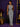 Lady Q’s Corner sleeveless pinstripe jumpsuit with a high neckline, cinched waist, and wide-leg trousers in monochrome.